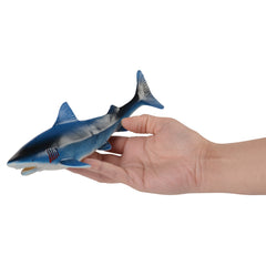 A realistic toy shark party favor being held in a hand